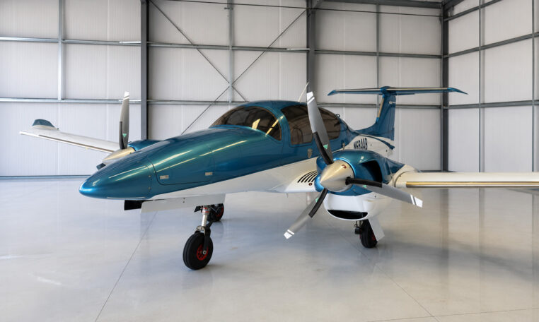 Teal and white twin-engine propeller airplane in hangar—modern private aircraft ready for flight, aviation and charter.