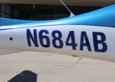 Airplane tail number N684AB on blue and white fuselage outside hangar, close-up of aircraft registration markings.