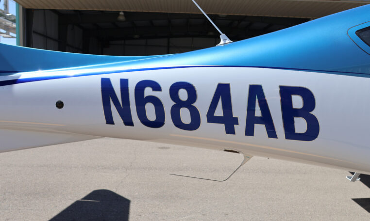Airplane tail number N684AB on blue and white fuselage outside hangar, close-up of aircraft registration markings.