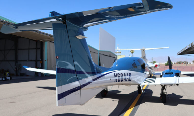 Sleek blue-and-white twin-engine private aircraft on tarmac by hangars, N684AB tail number visible