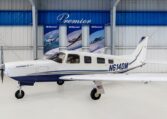 Piper Saratoga II TC N614DM single-engine aircraft in hangar at Premier, side view of blue-white plane.