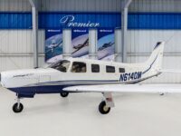 Piper Saratoga II TC N614DM single-engine aircraft in hangar at Premier, side view of blue-white plane.