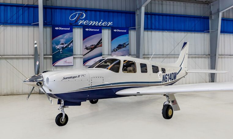 Piper Saratoga II TC single-engine piston airplane in hangar, white and blue livery, registration N614DM at Premier
