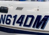 Airplane fuselage close-up showing blue aircraft tail number N614DM inside hangar.