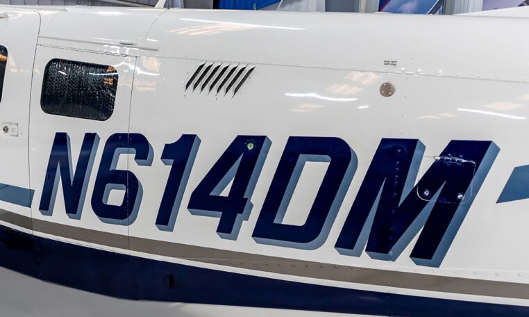 Airplane fuselage close-up showing blue aircraft tail number N614DM inside hangar.