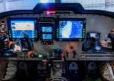 Light aircraft cockpit with Garmin G1000 glass avionics, dual yokes, PFD and MFD navigation displays in a hangar.