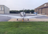 Rear view of single-engine aircraft parked on airport ramp near hangars, general aviation planes.