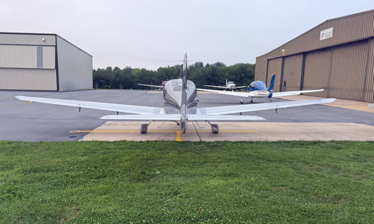 Rear view of single-engine aircraft parked on airport ramp near hangars, general aviation planes.