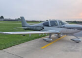Silver Cirrus single-engine airplane parked on airport ramp at sunrise, tail number N46JG.