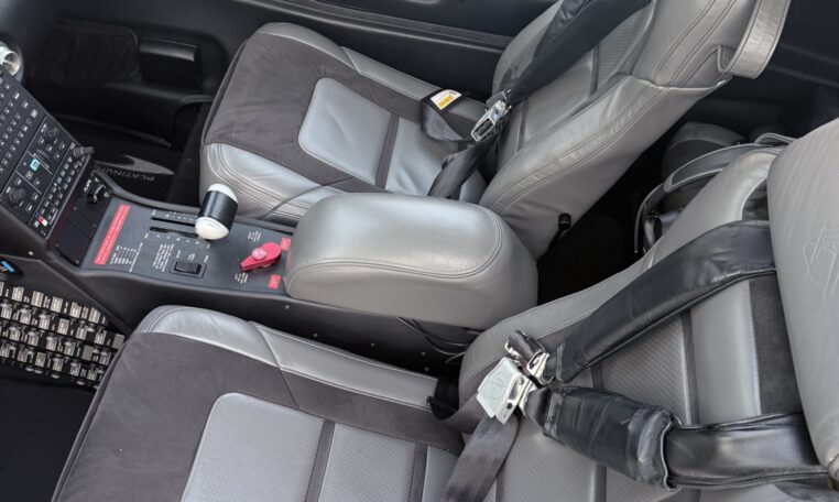 Cirrus aircraft cockpit interior with gray leather seats, 4-point harnesses, center console and avionics controls