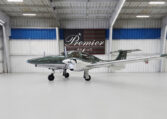 Green and white twin‑engine propeller plane inside Premier Aircraft hangar