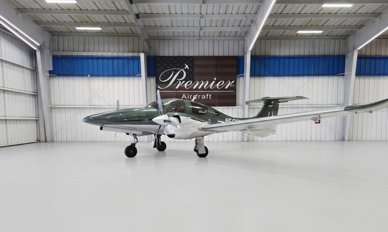Green and white twin‑engine propeller plane inside Premier Aircraft hangar
